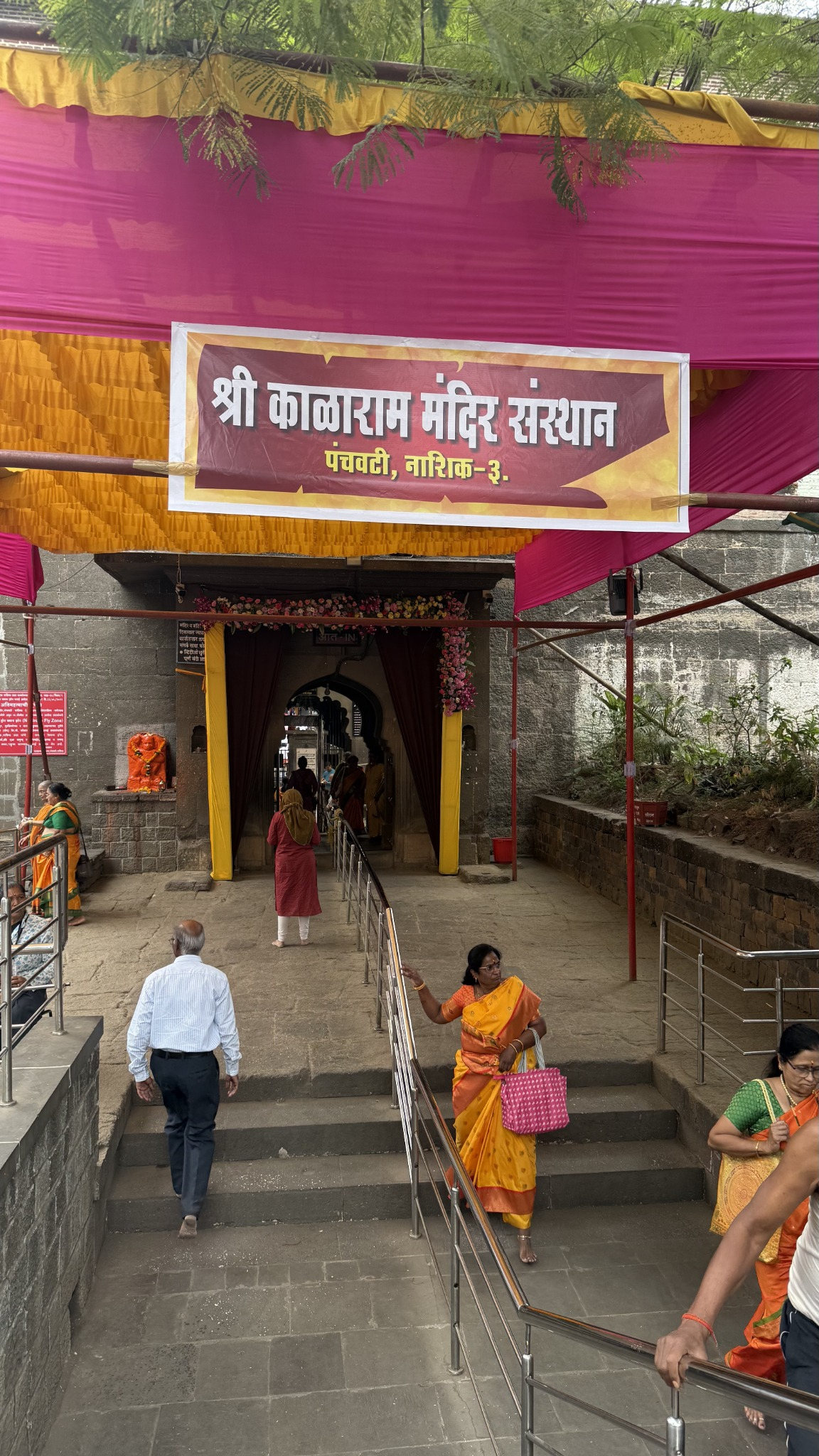 Decorated entrance to Shri Kalaram Mandir, with pilgrims and entrance railings.