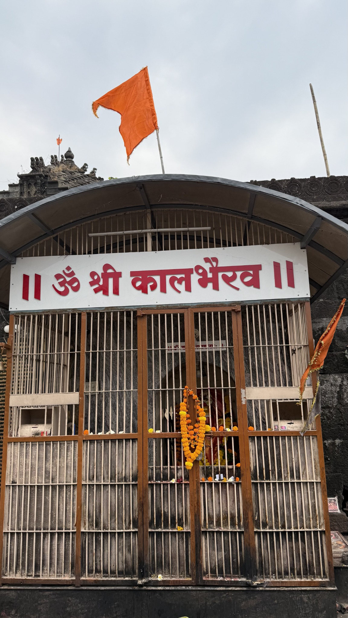 Shri Kalbhairav shrine in Panchavati with saffron flag and marigold garlands.